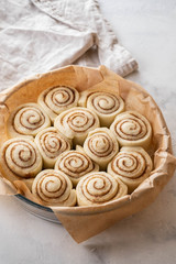 Obraz na płótnie Canvas Raw cinnamon rolls in baking plate on kitchen table. Copy space.