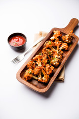Tandoori Gobi / Roasted cauliflower Tikka is a dry dish made by roasting Cauliflowers in Oven/Tandoor. It's  popular starter food from India. served with ketchup. selective focus