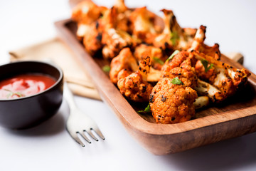 Tandoori Gobi / Roasted cauliflower Tikka is a dry dish made by roasting Cauliflowers in Oven/Tandoor. It's  popular starter food from India. served with ketchup. selective focus