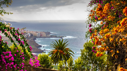 Puerto de la Cruz, Tenerife, Spain - A view of the harbor town of Puerto Cruz, along the coast, a dull day, with dark clouds in October in the fall and colorful flowering plants.