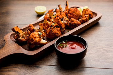 Tandoori Gobi / Roasted cauliflower Tikka is a dry dish made by roasting Cauliflowers in Oven/Tandoor. It's  popular starter food from India. served with ketchup. selective focus