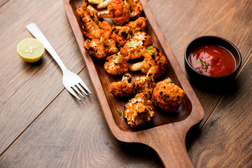 Tandoori Gobi / Roasted cauliflower Tikka is a dry dish made by roasting Cauliflowers in Oven/Tandoor. It's  popular starter food from India. served with ketchup. selective focus
