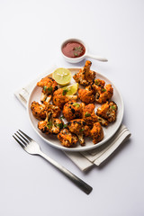 Tandoori Gobi / Roasted cauliflower Tikka is a dry dish made by roasting Cauliflowers in Oven/Tandoor. It's  popular starter food from India. served with ketchup. selective focus