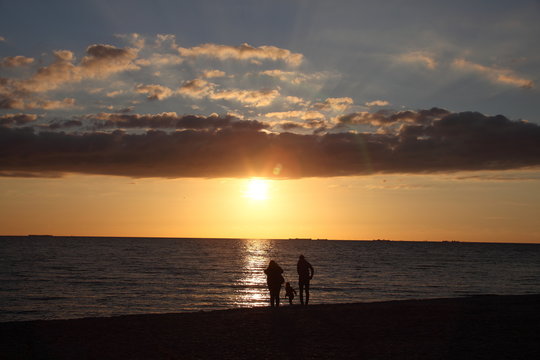 silhouettes d'une famille sur la plage au coucher du soleil