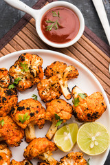 Tandoori Gobi / Roasted cauliflower Tikka is a dry dish made by roasting Cauliflowers in Oven/Tandoor. It's  popular starter food from India. served with ketchup. selective focus
