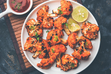 Tandoori Gobi / Roasted cauliflower Tikka is a dry dish made by roasting Cauliflowers in Oven/Tandoor. It's  popular starter food from India. served with ketchup. selective focus