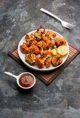 Tandoori Gobi / Roasted cauliflower Tikka is a dry dish made by roasting Cauliflowers in Oven/Tandoor. It's  popular starter food from India. served with ketchup. selective focus