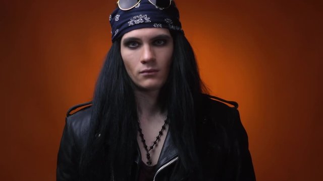 Rocker with bandana, leather jacket and beads, lifting his head, slow motion