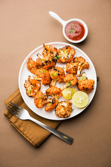Tandoori Gobi / Roasted cauliflower Tikka is a dry dish made by roasting Cauliflowers in Oven/Tandoor. It's  popular starter food from India. served with ketchup. selective focus