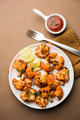 Tandoori Gobi / Roasted cauliflower Tikka is a dry dish made by roasting Cauliflowers in Oven/Tandoor. It's  popular starter food from India. served with ketchup. selective focus