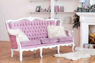 Pink velvet sofa with buttons and  fluffy pillows in front of the shelving