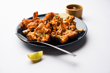 Tandoori Gobi / Roasted cauliflower Tikka is a dry dish made by roasting Cauliflowers in Oven/Tandoor. It's  popular starter food from India. served with ketchup. selective focus