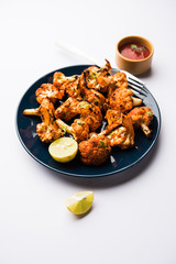 Tandoori Gobi / Roasted cauliflower Tikka is a dry dish made by roasting Cauliflowers in Oven/Tandoor. It's  popular starter food from India. served with ketchup. selective focus