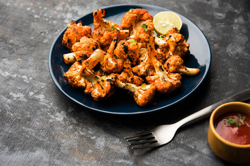 Tandoori Gobi / Roasted cauliflower Tikka is a dry dish made by roasting Cauliflowers in Oven/Tandoor. It's  popular starter food from India. served with ketchup. selective focus