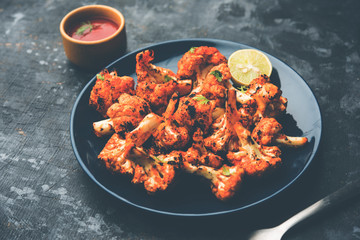 Tandoori Gobi / Roasted cauliflower Tikka is a dry dish made by roasting Cauliflowers in Oven/Tandoor. It's  popular starter food from India. served with ketchup. selective focus