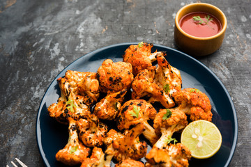 Tandoori Gobi / Roasted cauliflower Tikka is a dry dish made by roasting Cauliflowers in Oven/Tandoor. It's  popular starter food from India. served with ketchup. selective focus