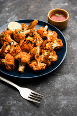 Tandoori Gobi / Roasted cauliflower Tikka is a dry dish made by roasting Cauliflowers in Oven/Tandoor. It's  popular starter food from India. served with ketchup. selective focus