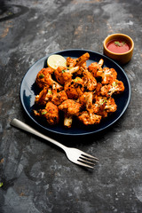 Tandoori Gobi / Roasted cauliflower Tikka is a dry dish made by roasting Cauliflowers in Oven/Tandoor. It's  popular starter food from India. served with ketchup. selective focus