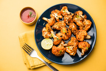 Tandoori Gobi / Roasted cauliflower Tikka is a dry dish made by roasting Cauliflowers in Oven/Tandoor. It's  popular starter food from India. served with ketchup. selective focus