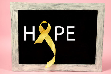 Yellow ribbon symbolic color for Sarcoma Bone cancer awareness and suicide prevention on aged wooden advertising board. The cancer, health, help, care, support, hope, illness, healthcare concept