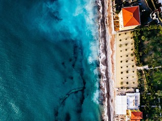 Aerial view of beach and waves. Turquoise sea water and palms, summer landscape from above.