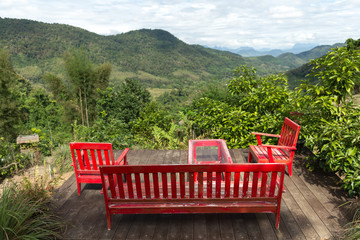 Red furniture in front of a Panoramic view of green Valley covered with lush green forests and Mekong river near Luang Prabang in northern Laos
