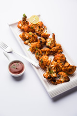 Tandoori Gobi / Roasted cauliflower Tikka is a dry dish made by roasting Cauliflowers in Oven/Tandoor. It's  popular starter food from India. served with ketchup. selective focus