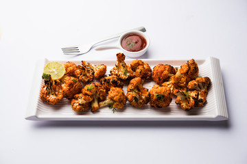 Tandoori Gobi / Roasted cauliflower Tikka is a dry dish made by roasting Cauliflowers in Oven/Tandoor. It's  popular starter food from India. served with ketchup. selective focus