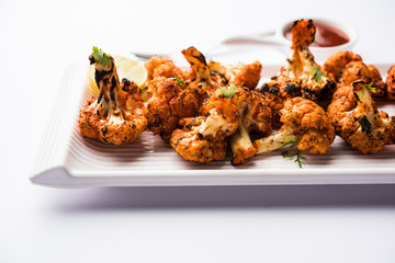 Tandoori Gobi / Roasted cauliflower Tikka is a dry dish made by roasting Cauliflowers in Oven/Tandoor. It's  popular starter food from India. served with ketchup. selective focus