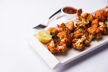 Tandoori Gobi / Roasted cauliflower Tikka is a dry dish made by roasting Cauliflowers in Oven/Tandoor. It's  popular starter food from India. served with ketchup. selective focus