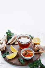 Hot tea with ginger, lemon, honey and mint leaves on white table.Tea against cold.Healthcare concept.Useful tea for immunity.Eyer bird view
