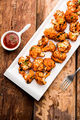 Tandoori Gobi / Roasted cauliflower Tikka is a dry dish made by roasting Cauliflowers in Oven/Tandoor. It's  popular starter food from India. served with ketchup. selective focus