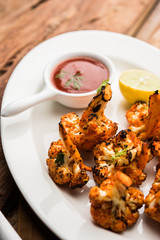 Tandoori Gobi / Roasted cauliflower Tikka is a dry dish made by roasting Cauliflowers in Oven/Tandoor. It's  popular starter food from India. served with ketchup. selective focus