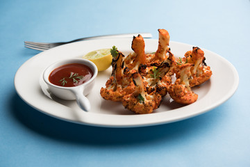 Tandoori Gobi / Roasted cauliflower Tikka is a dry dish made by roasting Cauliflowers in Oven/Tandoor. It's  popular starter food from India. served with ketchup. selective focus