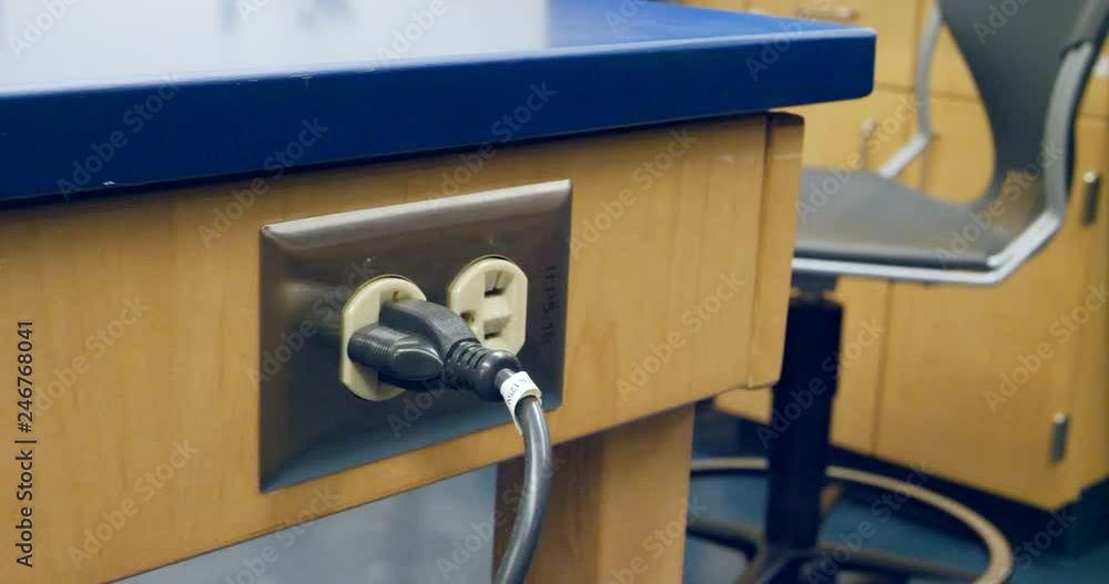 Poster close up on a scientist plugging in a piece of medical research technology in an electrical outlet d