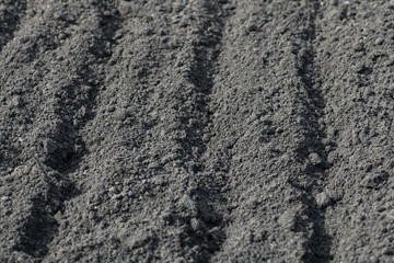 Empty furrows on black ground in a farm field in early spring. Preparation of soil for planting...