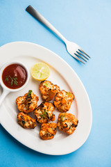 Tandoori Gobi / Roasted cauliflower Tikka is a dry dish made by roasting Cauliflowers in Oven/Tandoor. It's  popular starter food from India. served with ketchup. selective focus