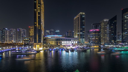 Aerial vew of Dubai Marina with shoping mall, restaurants, towers and yachts night timelapse, United Arab Emirates.