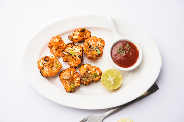 Tandoori Gobi / Roasted cauliflower Tikka is a dry dish made by roasting Cauliflowers in Oven/Tandoor. It's  popular starter food from India. served with ketchup. selective focus
