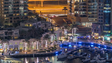 Luxury Dubai Marina canal with passing boats and promenade night timelapse, Dubai, United Arab...