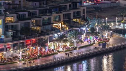 Luxury Dubai Marina canal with passing boats and promenade night timelapse, Dubai, United Arab...