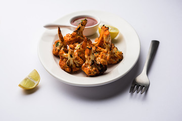 Tandoori Gobi / Roasted cauliflower Tikka is a dry dish made by roasting Cauliflowers in Oven/Tandoor. It's  popular starter food from India. served with ketchup. selective focus
