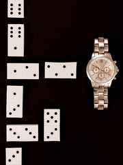 top view of luxury wristwatch lying near dominoes isolated on black