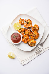 Tandoori Gobi / Roasted cauliflower Tikka is a dry dish made by roasting Cauliflowers in Oven/Tandoor. It's  popular starter food from India. served with ketchup. selective focus
