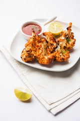 Tandoori Gobi / Roasted cauliflower Tikka is a dry dish made by roasting Cauliflowers in Oven/Tandoor. It's  popular starter food from India. served with ketchup. selective focus