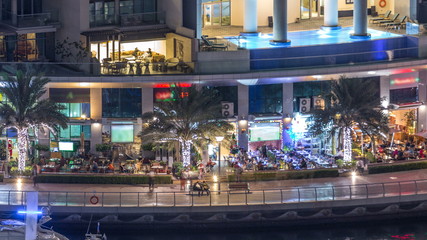 Luxury Dubai Marina canal with passing boats and promenade night timelapse, Dubai, United Arab Emirates