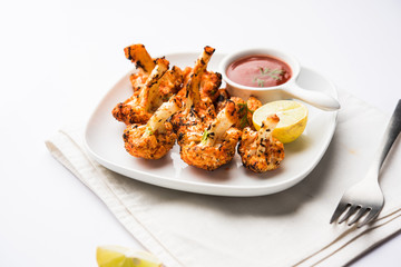 Tandoori Gobi / Roasted cauliflower Tikka is a dry dish made by roasting Cauliflowers in Oven/Tandoor. It's  popular starter food from India. served with ketchup. selective focus