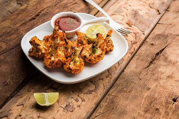 Tandoori Gobi / Roasted cauliflower Tikka is a dry dish made by roasting Cauliflowers in Oven/Tandoor. It's  popular starter food from India. served with ketchup. selective focus