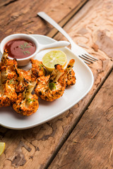Tandoori Gobi / Roasted cauliflower Tikka is a dry dish made by roasting Cauliflowers in Oven/Tandoor. It's  popular starter food from India. served with ketchup. selective focus