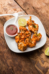 Tandoori Gobi / Roasted cauliflower Tikka is a dry dish made by roasting Cauliflowers in Oven/Tandoor. It's  popular starter food from India. served with ketchup. selective focus